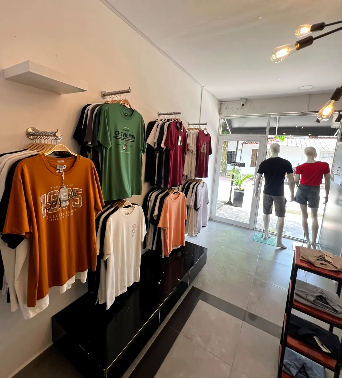 Pared de camisetas de colores junto a la entrada de la tienda