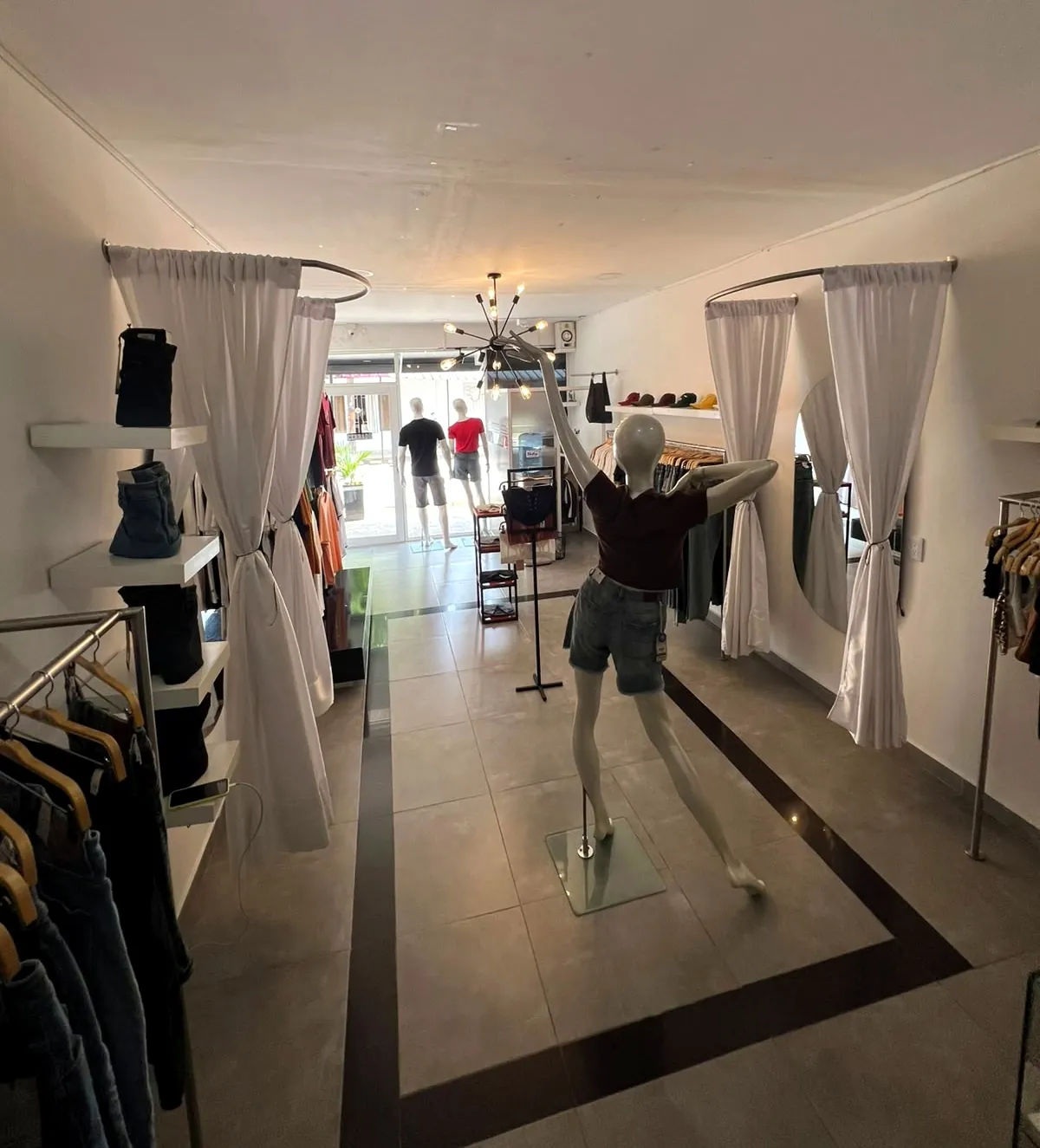 Probadores con cortinas blancas y maniquí con jean